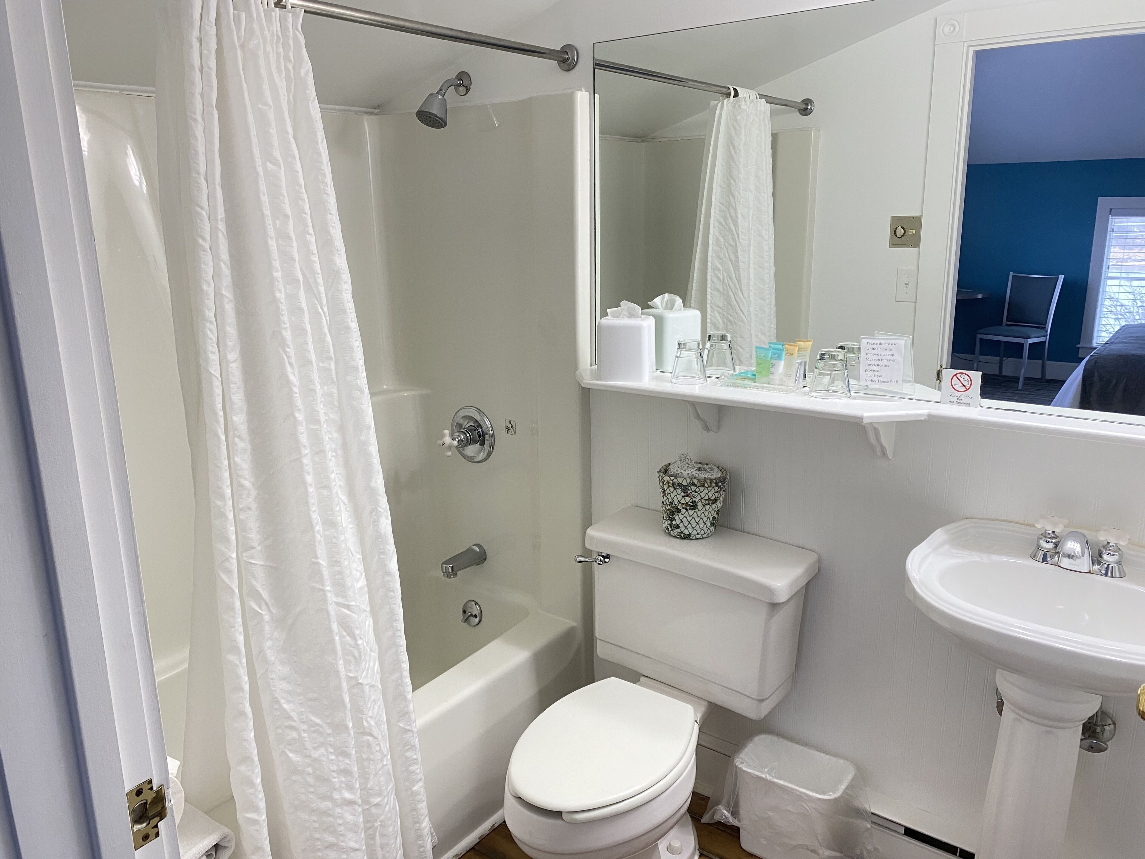 A bathroom with a shower, toilet, sink, and a mirror.