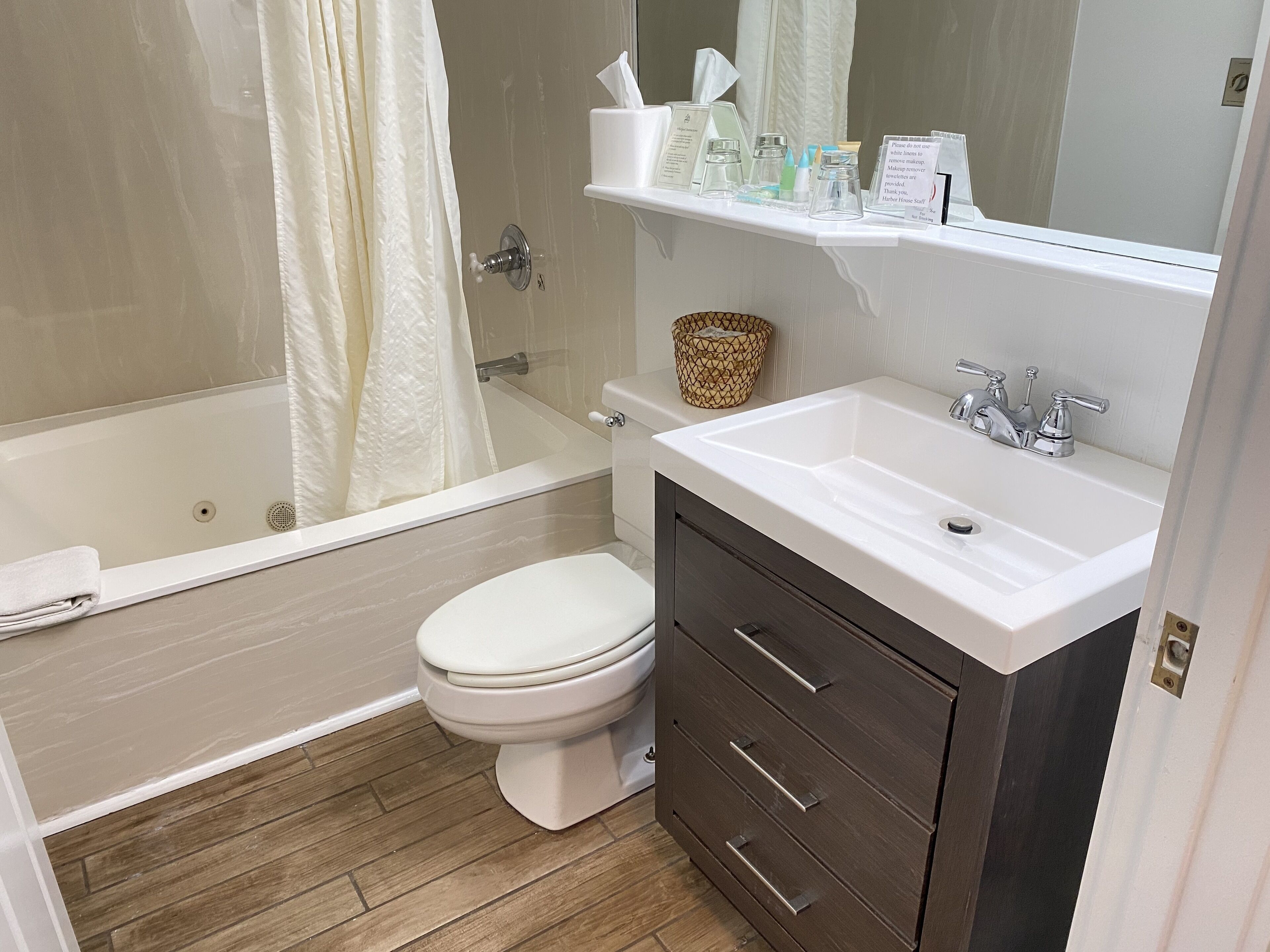 A bathroom with a bathtub, toilet, and vanity with drawers.