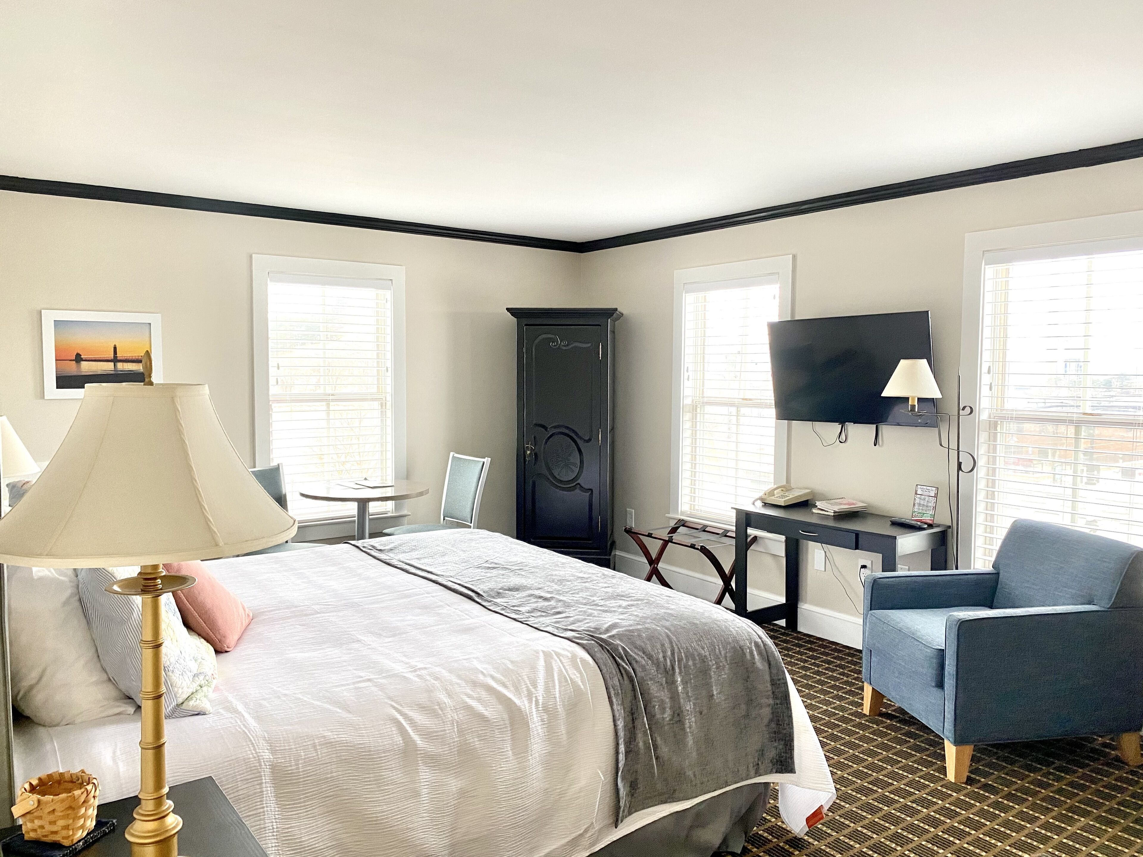 A hotel room with a bed, a desk, a chair, a TV, and a wardrobe.