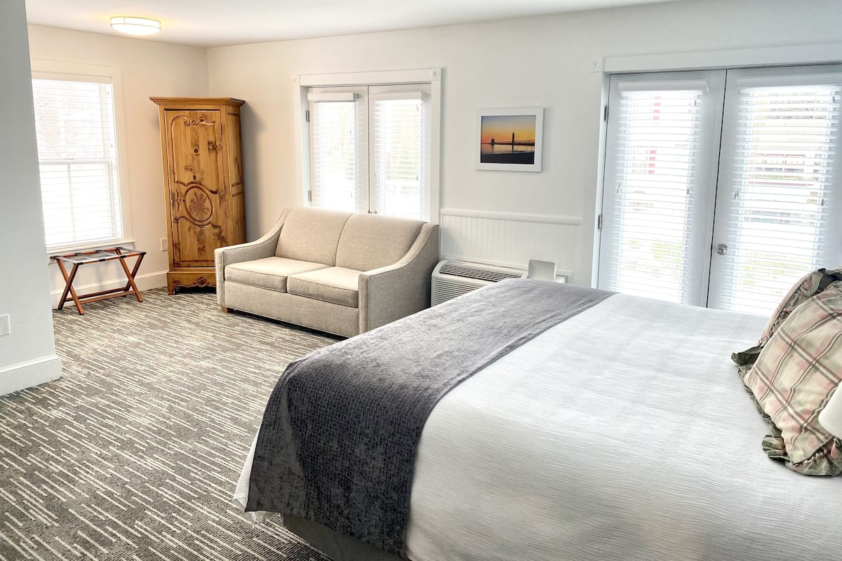 Un dormitorio con cama, sofá, armario de madera y radiador.