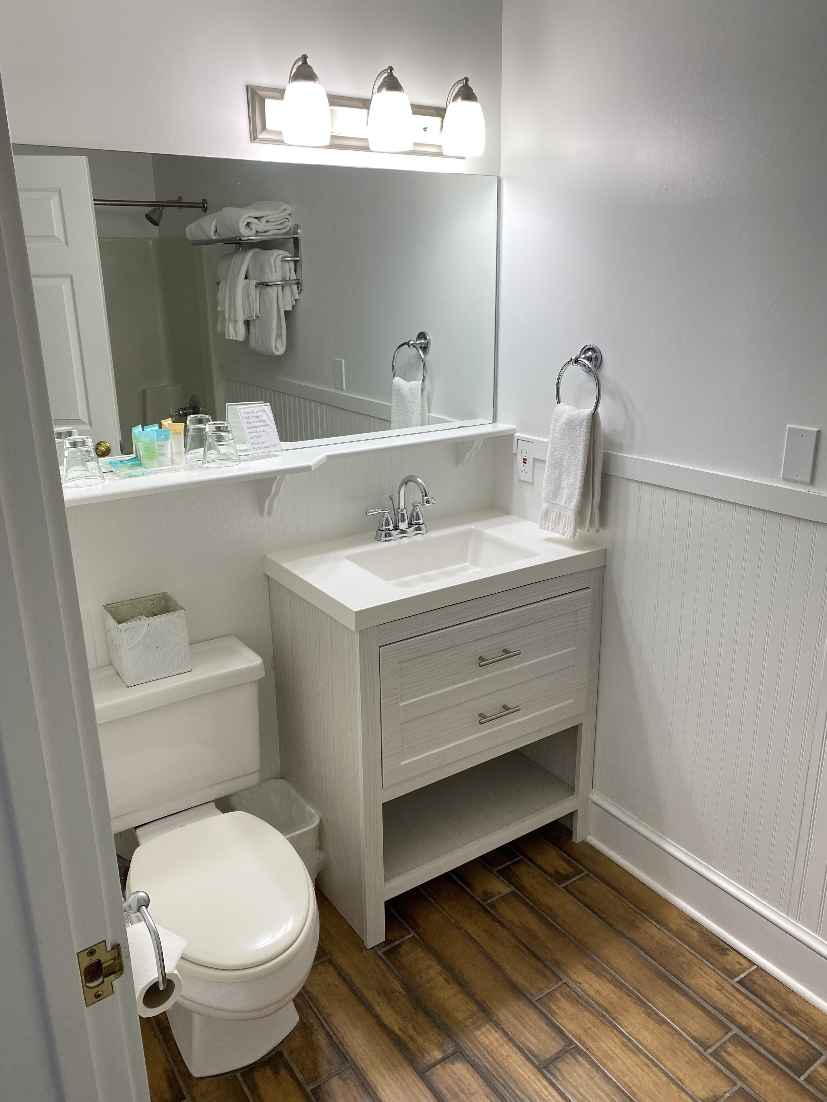 Une petite salle de bain avec un lavabo blanc, des toilettes et un miroir au-dessus du lavabo.