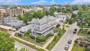 A large, multi-story building with a prominent balcony, surrounded by well-maintained lawns and a clear street view. - Harbor House Inn (Grand Haven)