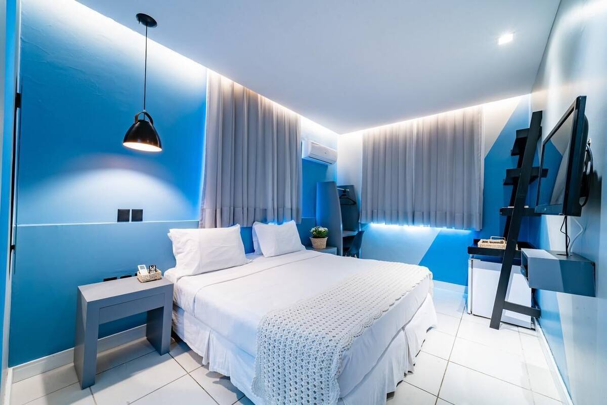 A modern bedroom with a large bed, a bedside table, a TV, and a desk with a chair.