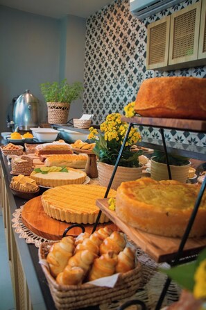 A buffet with various baked goods and a decorative plant. - Fortpraia Hotel (Fortaleza)