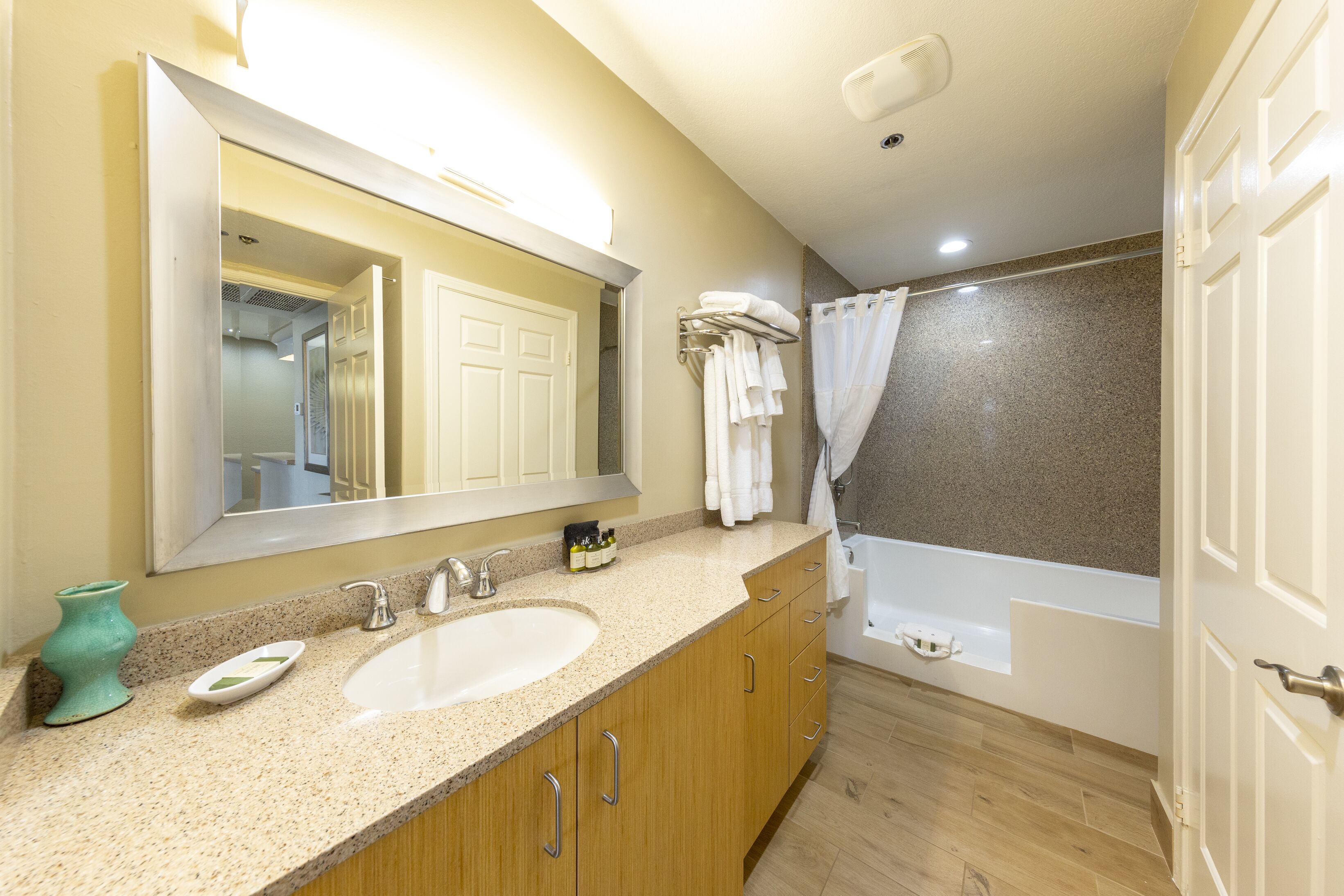A bathroom with a sink, mirror, and bathtub.