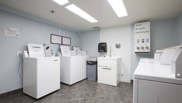Une buanderie équipée de plusieurs machines à laver, d’une poubelle et d’un distributeur de savon.