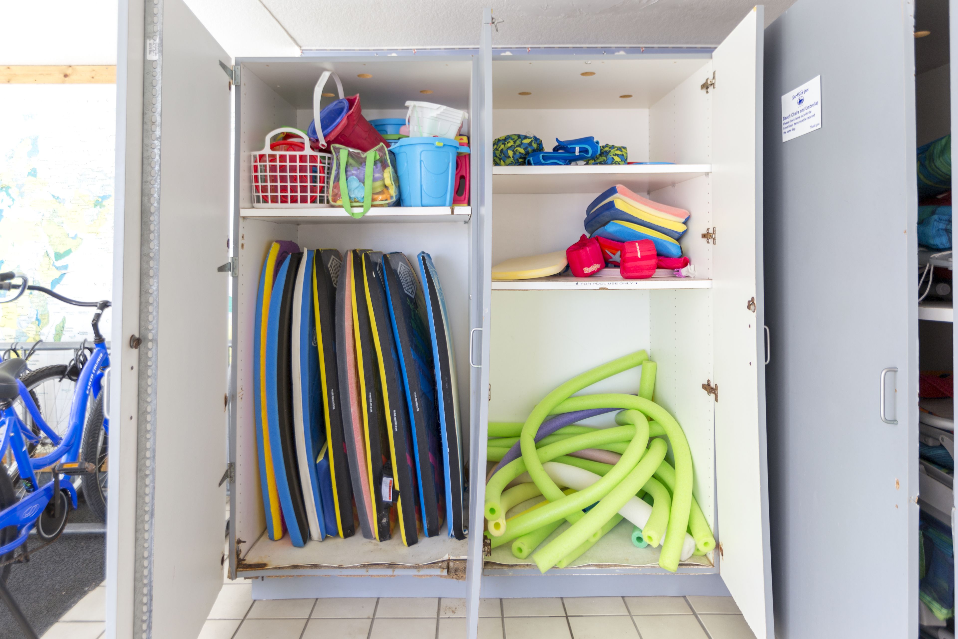A storage room with shelves containing various items like bags, shoes, and sports equipment.