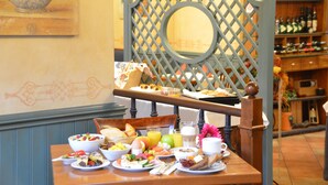 A breakfast table set with various dishes, a fruit bowl, and a wine rack in the background. - Wohlfühl - Hotel Neu Heidelberg - Hotel Heidelberg (Heidelberg)