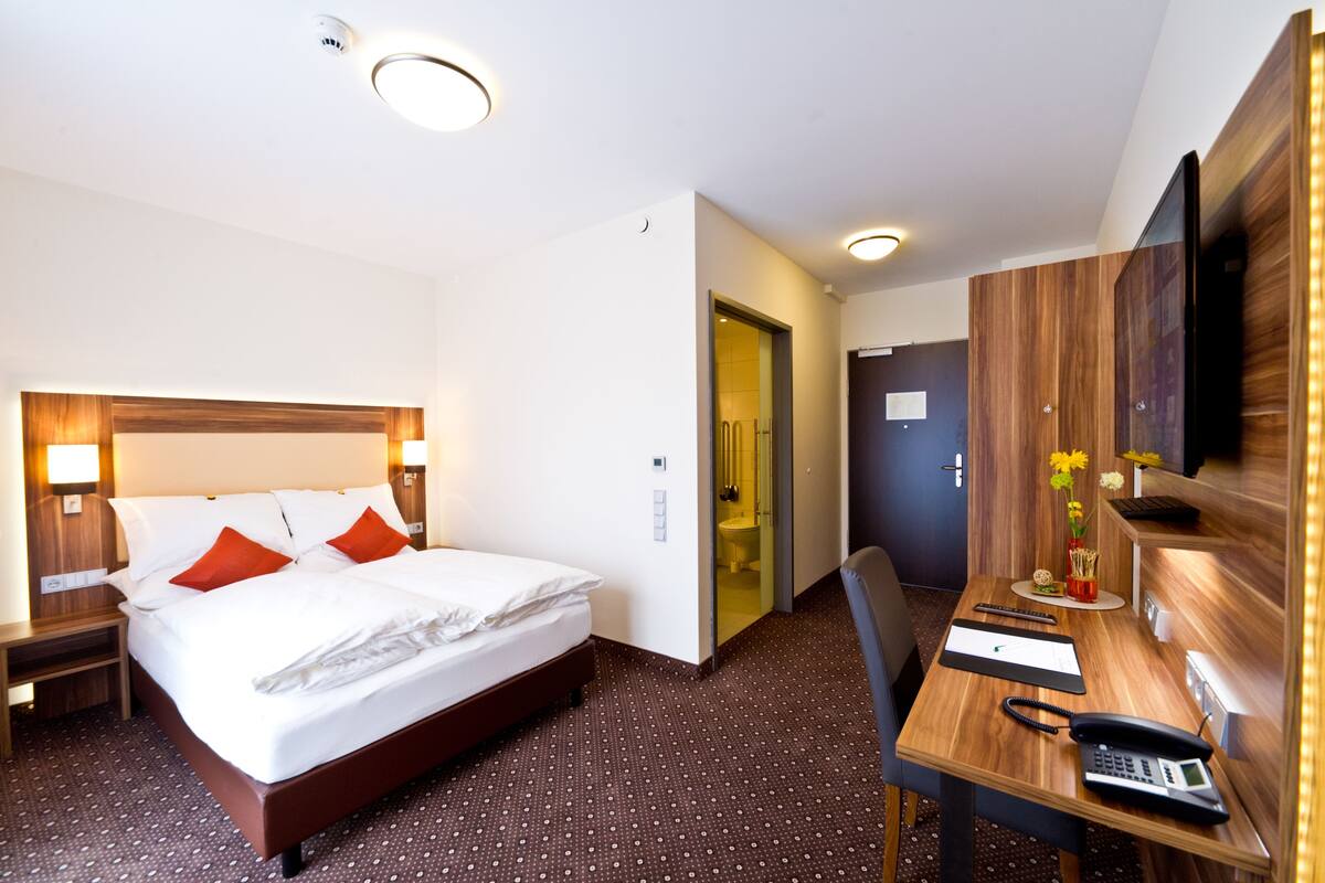 Een hotelkamer met een groot bed, nachtkastjes, een bureau met telefoon en een televisie.