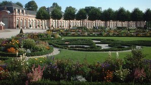 A formal garden with manicured lawns, flower beds, and a classical building with columns. - Wohlfühl - Hotel Neu Heidelberg - Hotel Heidelberg (Heidelberg)