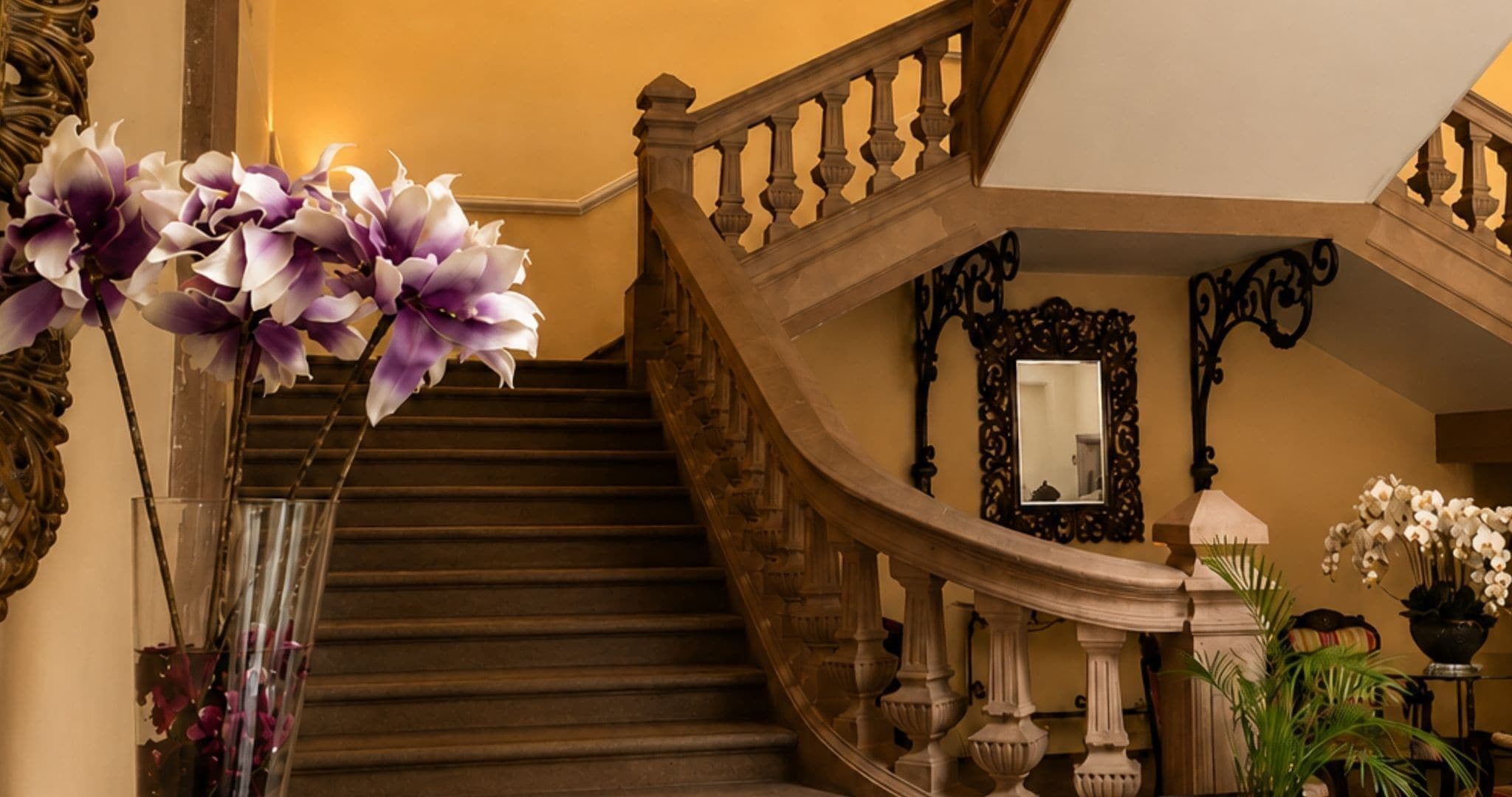A grand staircase with ornate balustrades and a mirror above it.
