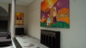 Un pasillo con un gran mural en la pared que muestra una escena vibrante con gente y animales.