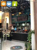 Interior de una cafetería con una pizarra de menú, una barra de atención y una vitrina de vidrio.