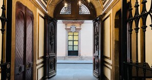 Un couloir orné de portes richement décorées et doté d’une fenêtre avec des vitres grillagées.