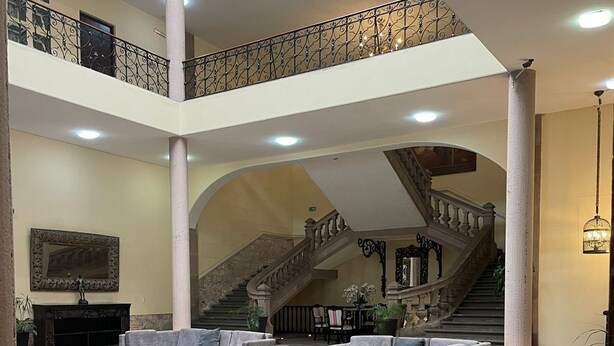 Un vestíbulo amplio con una zona de estar central, una escalera y una chimenea.