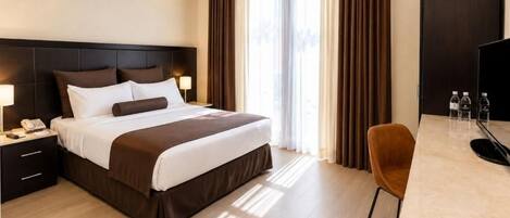 Una habitación de hotel con cama, mesita de noche, lámpara y escritorio con silla.