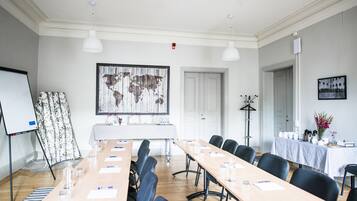 Un salón de conferencias con una larga mesa, sillas, una pizarra y un mapa del mundo en la pared.