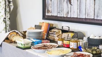 Uma mesa de buffet com diversos alimentos, incluindo pão, queijo, carnes e acompanhamentos.