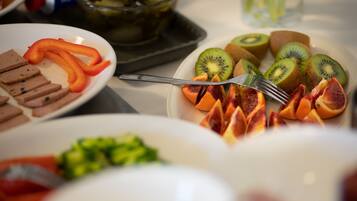 A table with various food items including sliced meats, vegetables, and fruits.