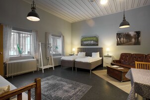Una habitación de hotel moderna con una cama doble, un sofá, una mesa de comedor y un amplio ventanal con cortinas.