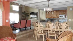 A dining area with a table and chairs, a kitchen in the background, and a living room with a sofa. - Sunrise Beach Club and Villas (Paradise Island)