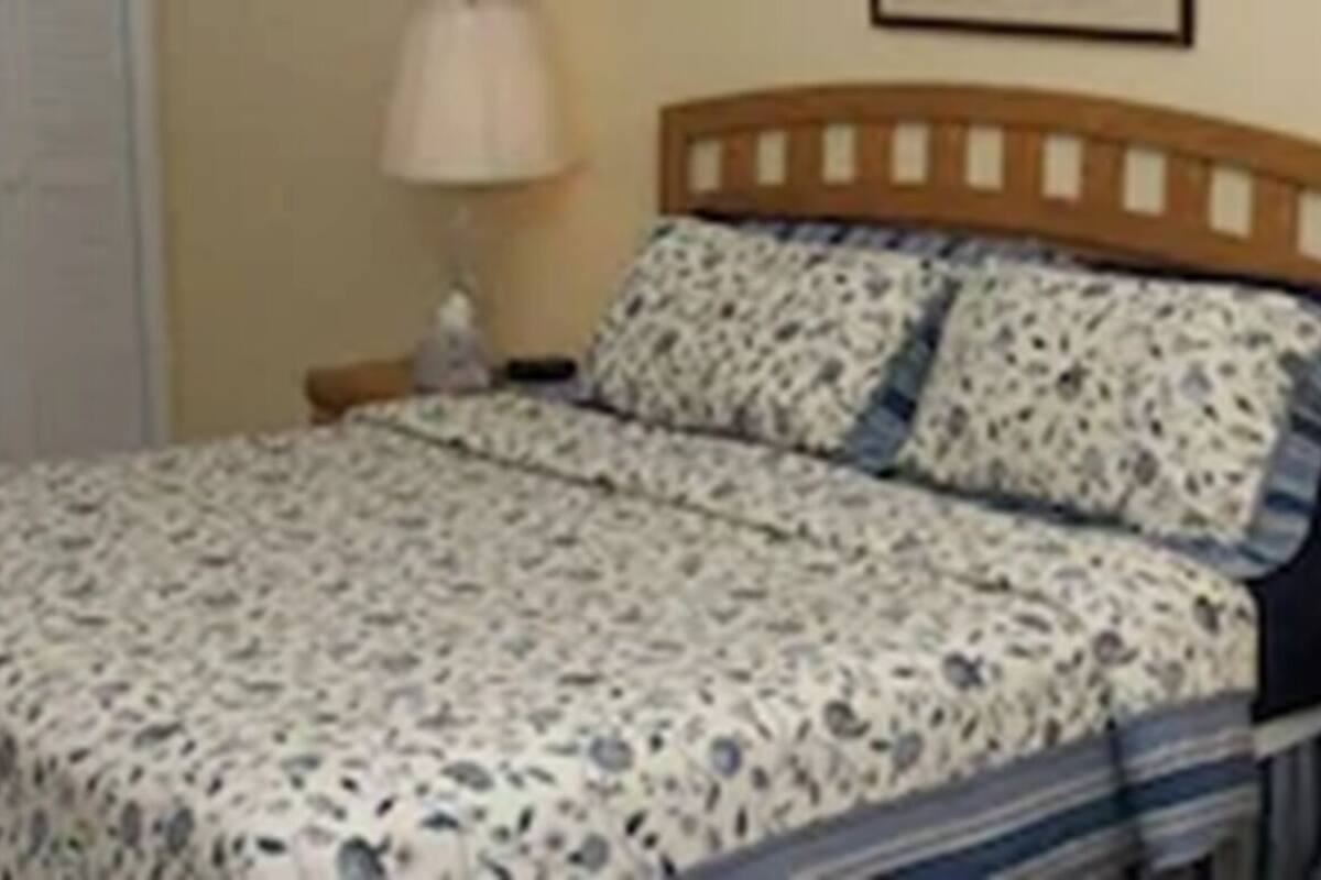 A neatly arranged bedroom with a bed, bedside tables, a dresser, and a mirror.