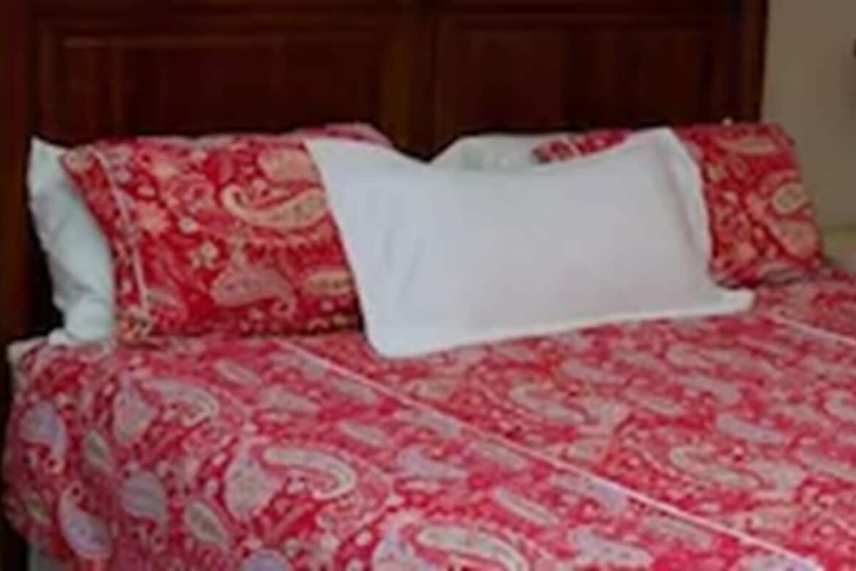 A bed with a patterned bedspread, two bedside lamps, and a wooden headboard.