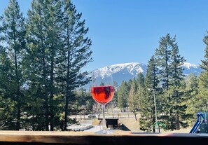 A glass of red wine with a mountain view in the background. - The Piccadilly Motel (Radium Hot Springs)