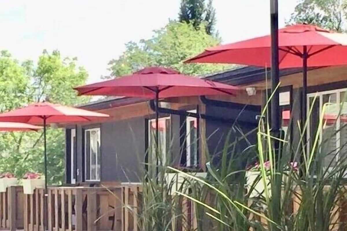 Outdoor seating with red umbrellas, wooden deck, and potted plants.