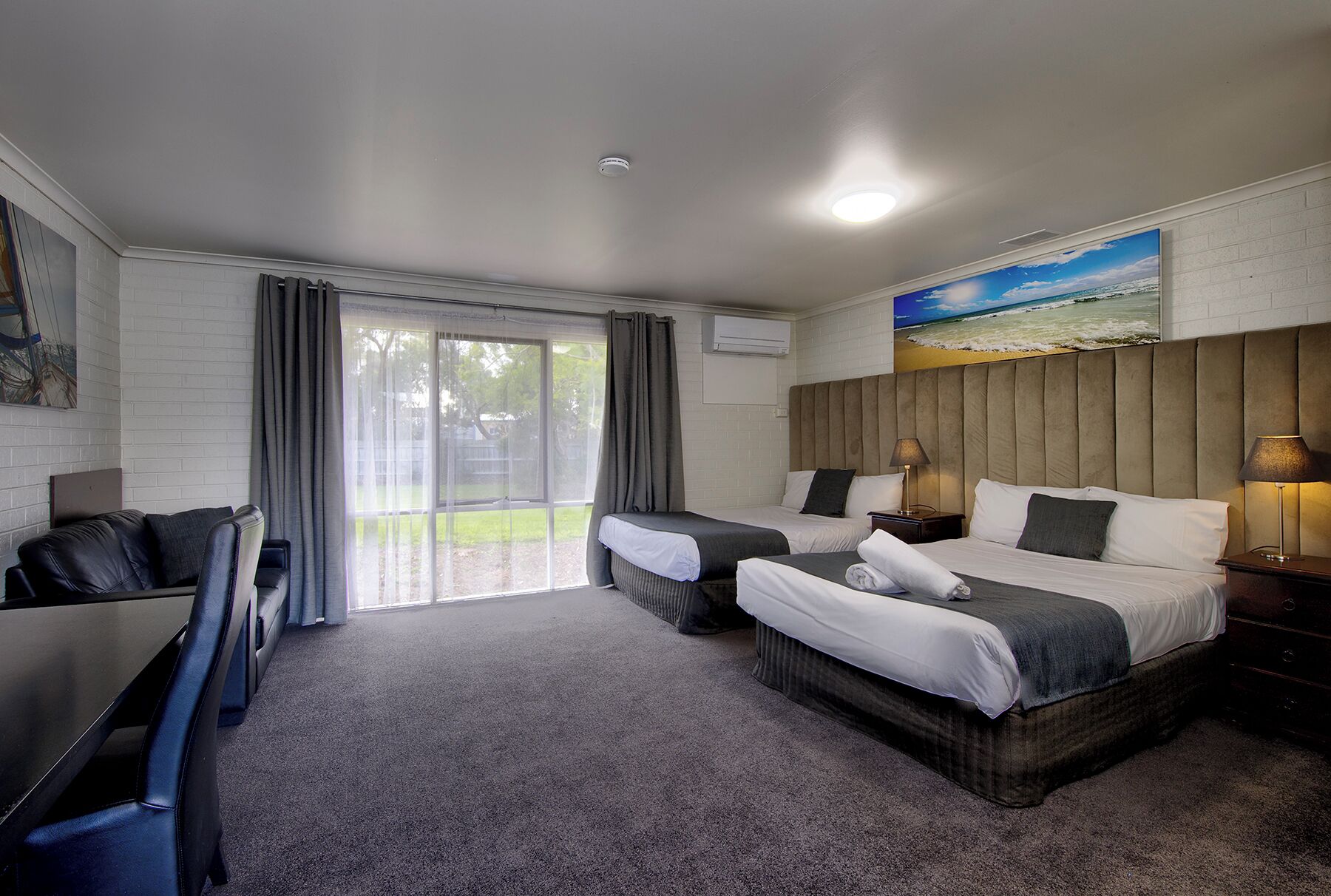 A hotel room with two beds, a TV, and a large window with curtains.