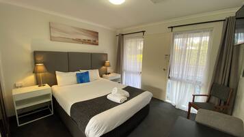 Habitación de hotel con una cama grande, dos mesitas de noche con lámparas, una silla y un escritorio.