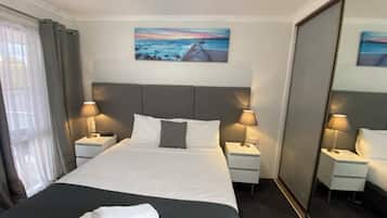 Une chambre d’hôtel avec un grand lit, deux tables de chevet avec des lampes, un tableau au mur et un miroir.