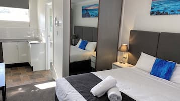 Una habitación de hotel con cama, escritorio, espejo y un cuadro en la pared.