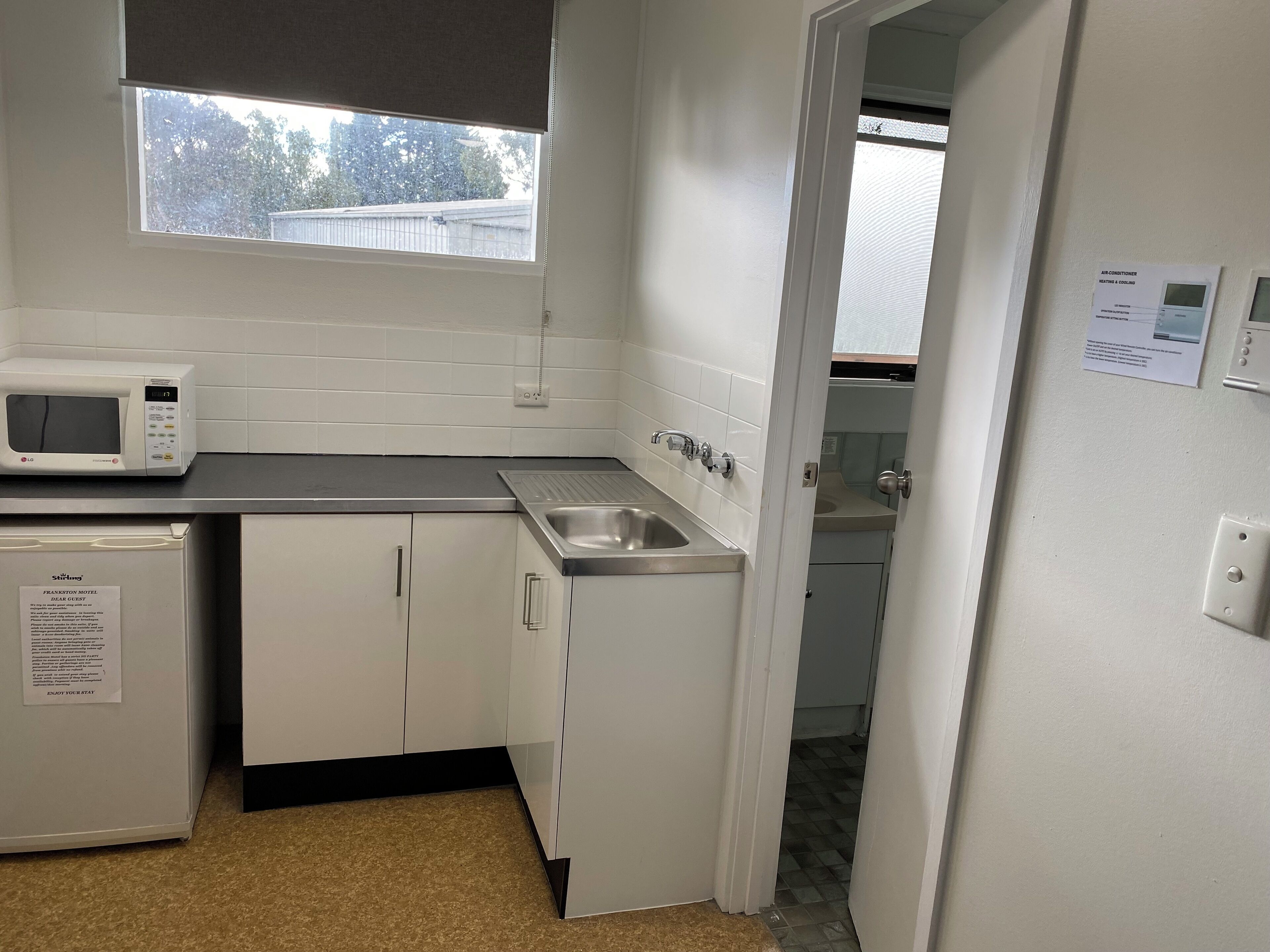 A compact kitchenette with a microwave, sink, and a refrigerator.
