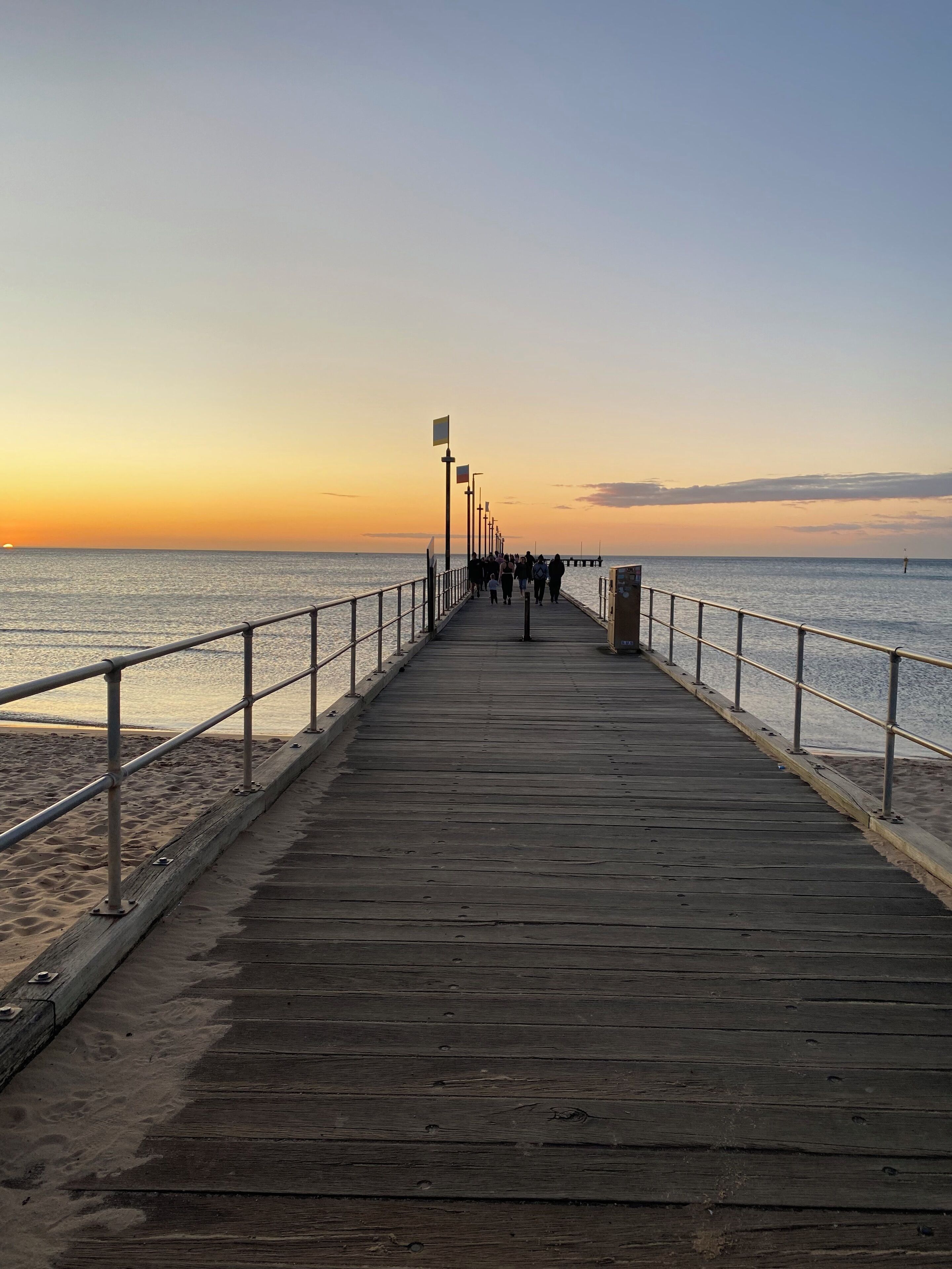 A wooden pier extending into calm waters with a clear sky.
