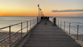 A wooden pier extending into calm waters with a clear sky.