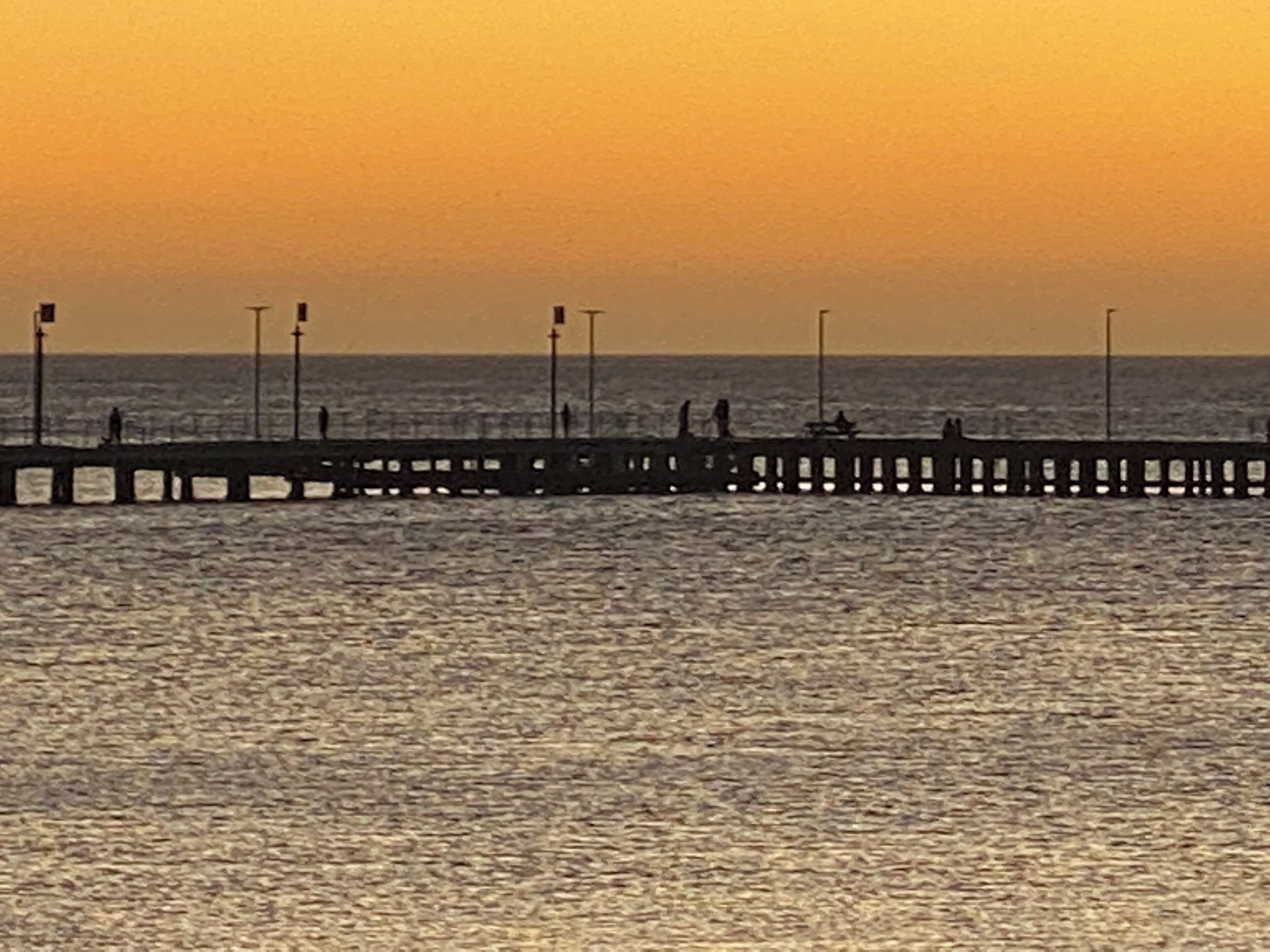 A pier extending into calm waters at sunset.