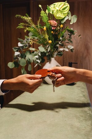 Eine Hand hält einen Schlüsselbund, im Hintergrund steht eine Blumenvase.