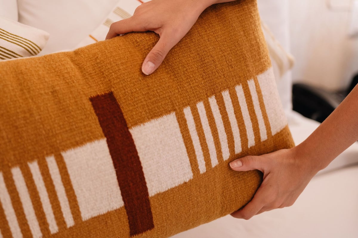 A person holding a patterned throw pillow with a geometric design.