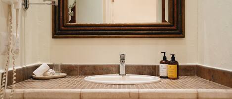 A bathroom with a sink, mirror, and toiletries.