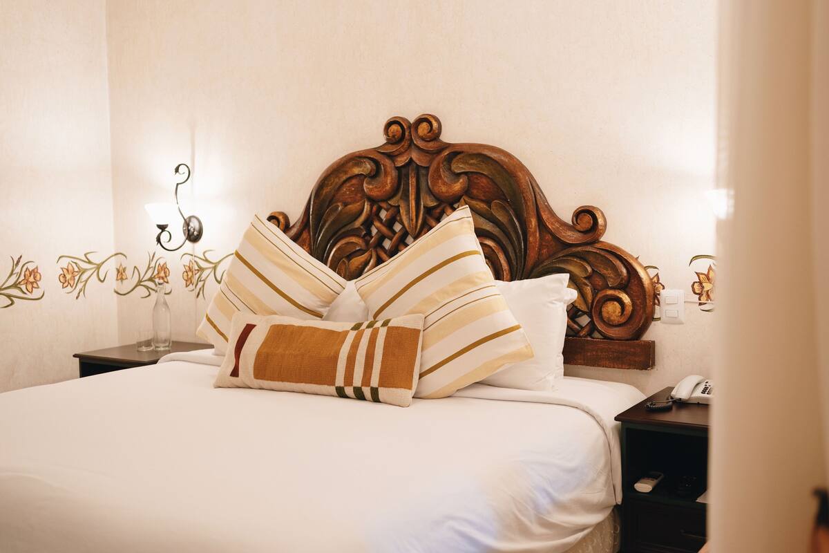 A neatly made bed with striped pillows and a wooden headboard.