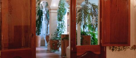A wooden door with a mirror, leading to a room with a bed and a potted plant.