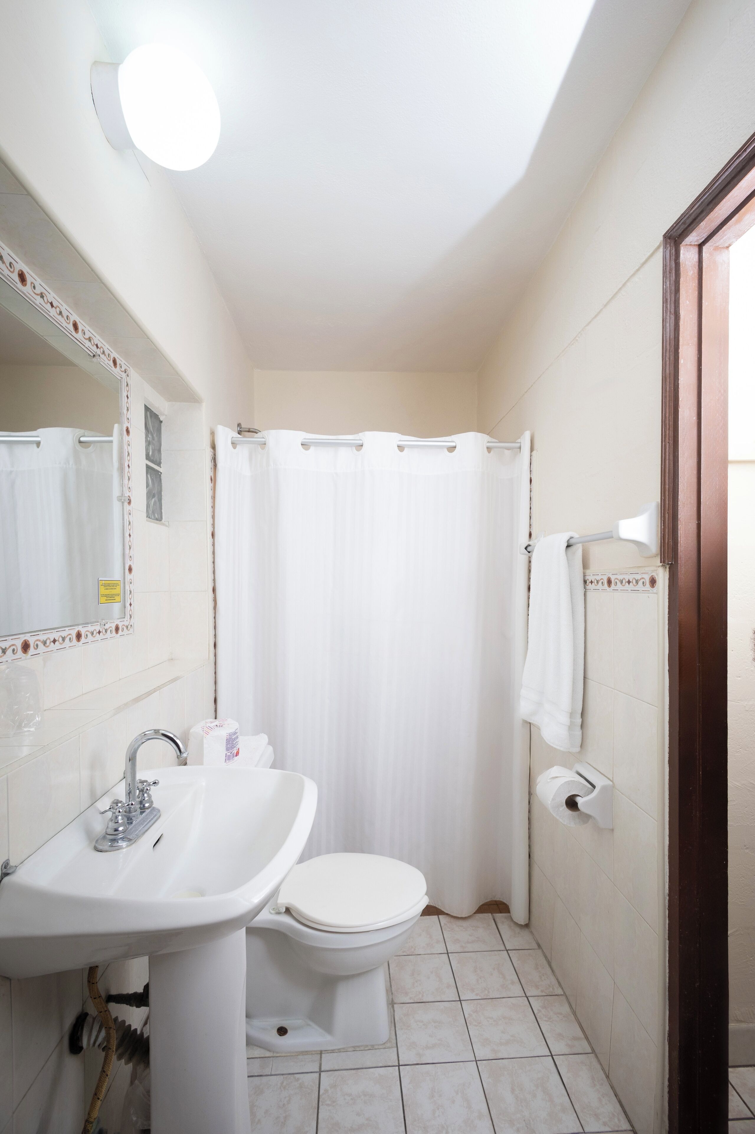 A small, clean bathroom with a white sink, toilet, and shower curtain.