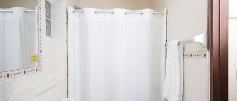A small, clean bathroom with a white sink, toilet, and shower curtain.