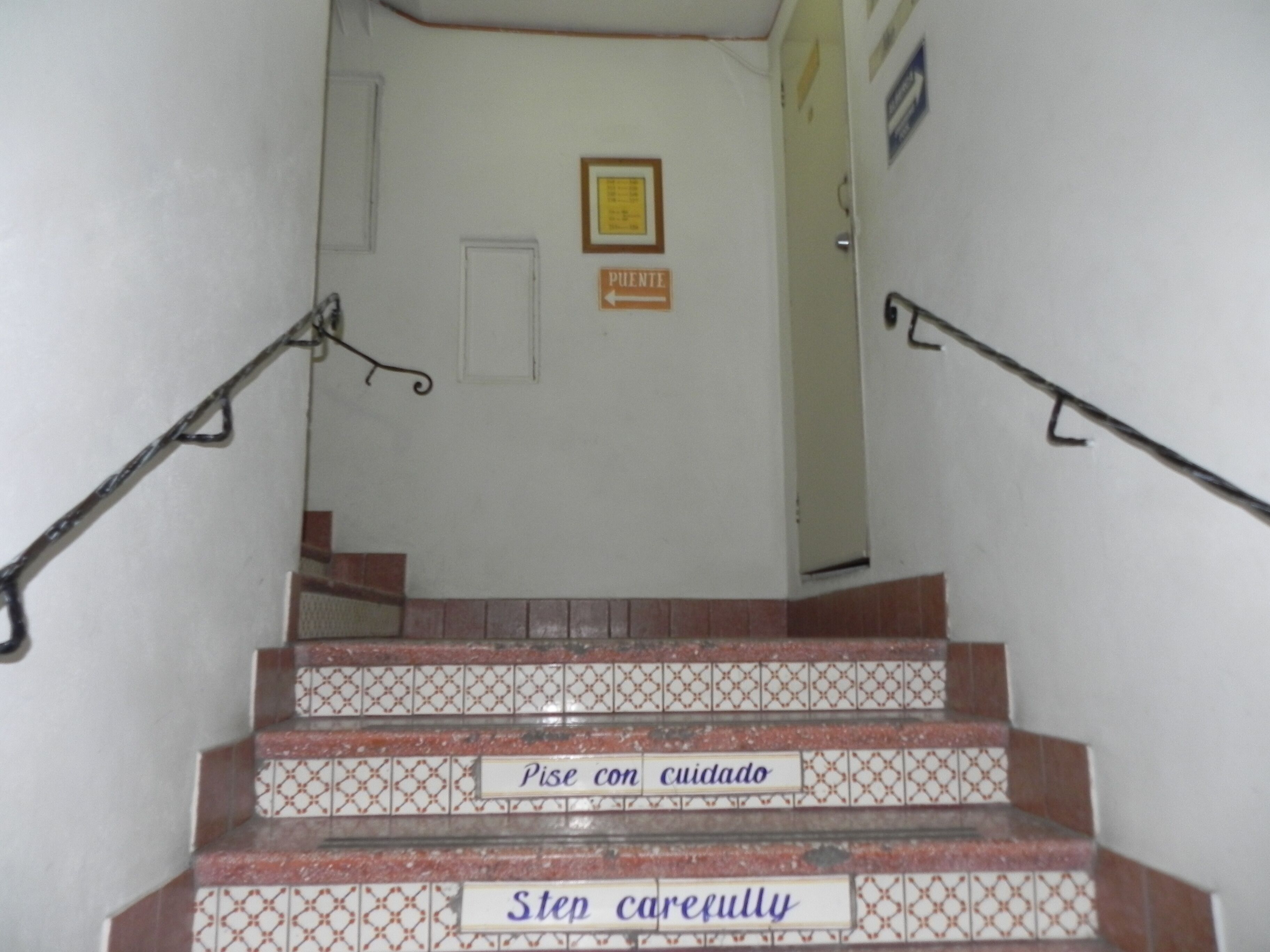 A staircase with handrails and steps marked with safety instructions in Spanish and English.
