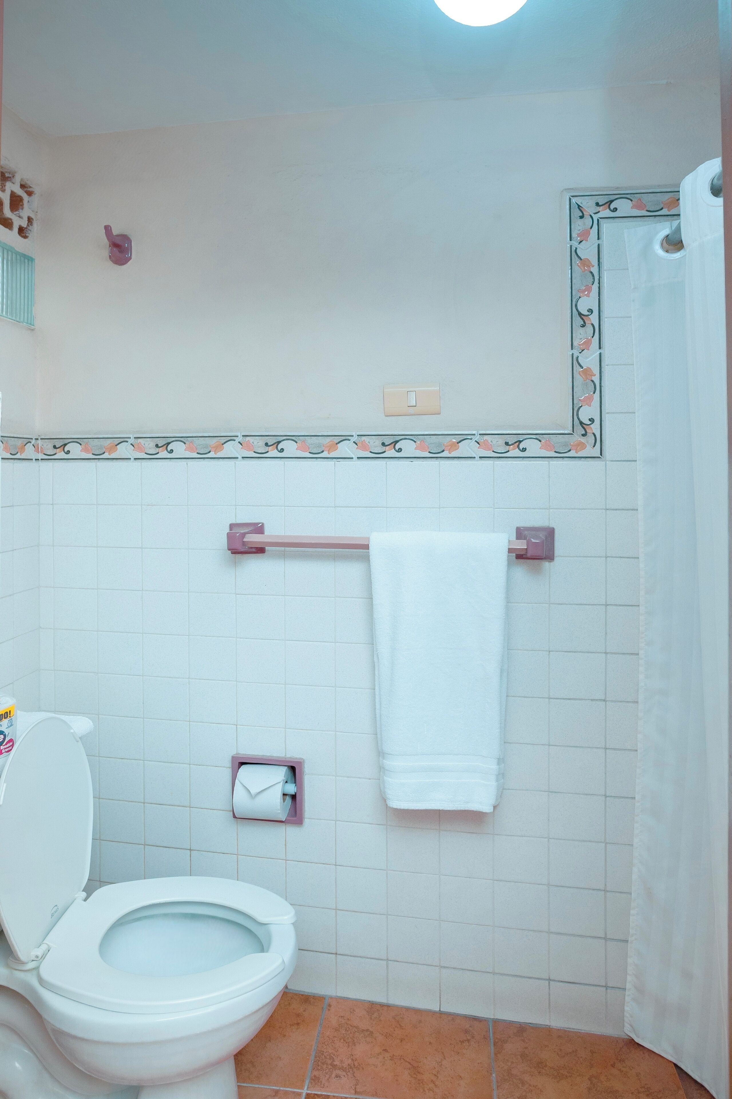 A bathroom with a toilet, a towel rack, and a toilet paper holder.
