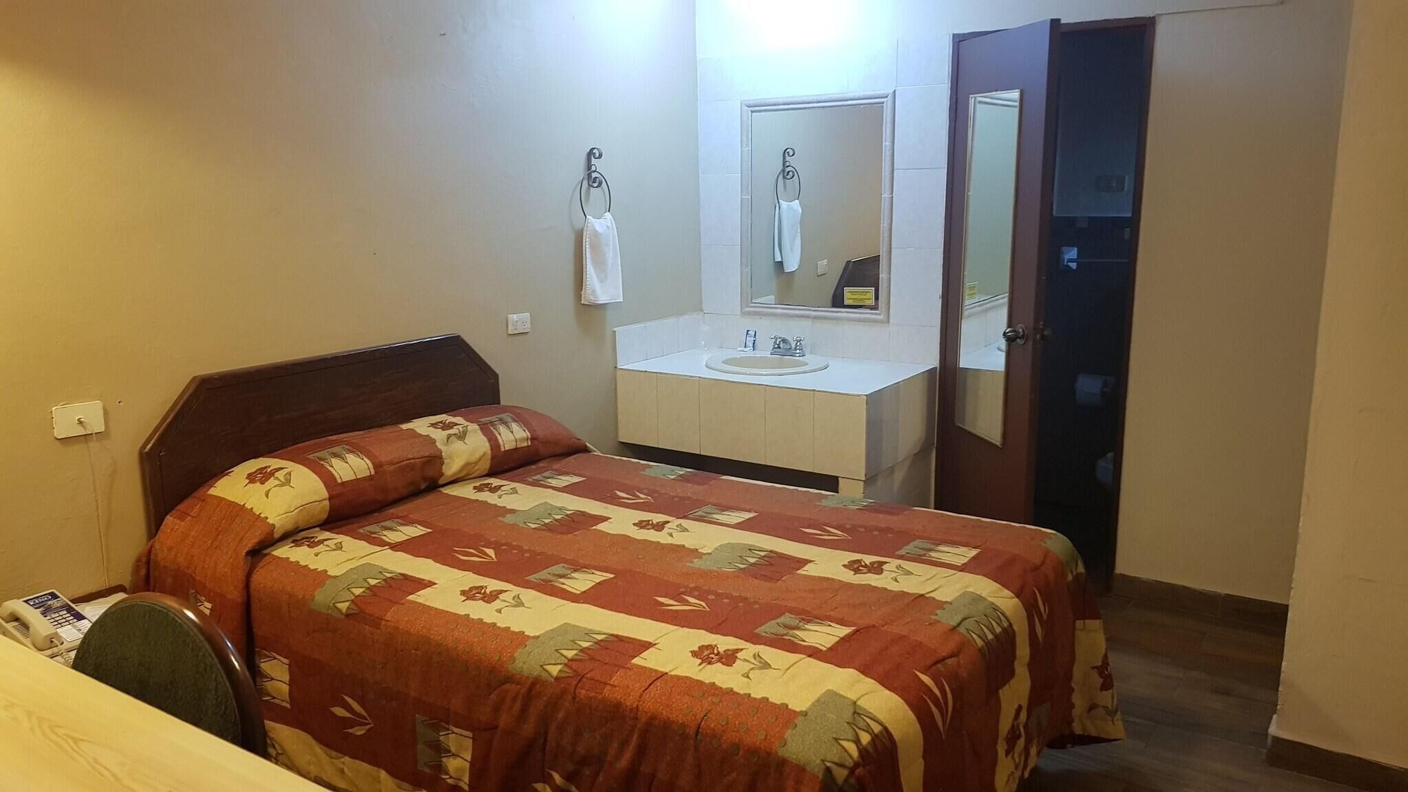 Ein Hotelzimmer mit Bett, Bad mit Waschbecken und Spiegel sowie einer Tür.