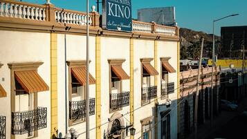 Un hotel con un cartel que dice 'HOTEL SUITES KINO' y una persona caminando por la acera.