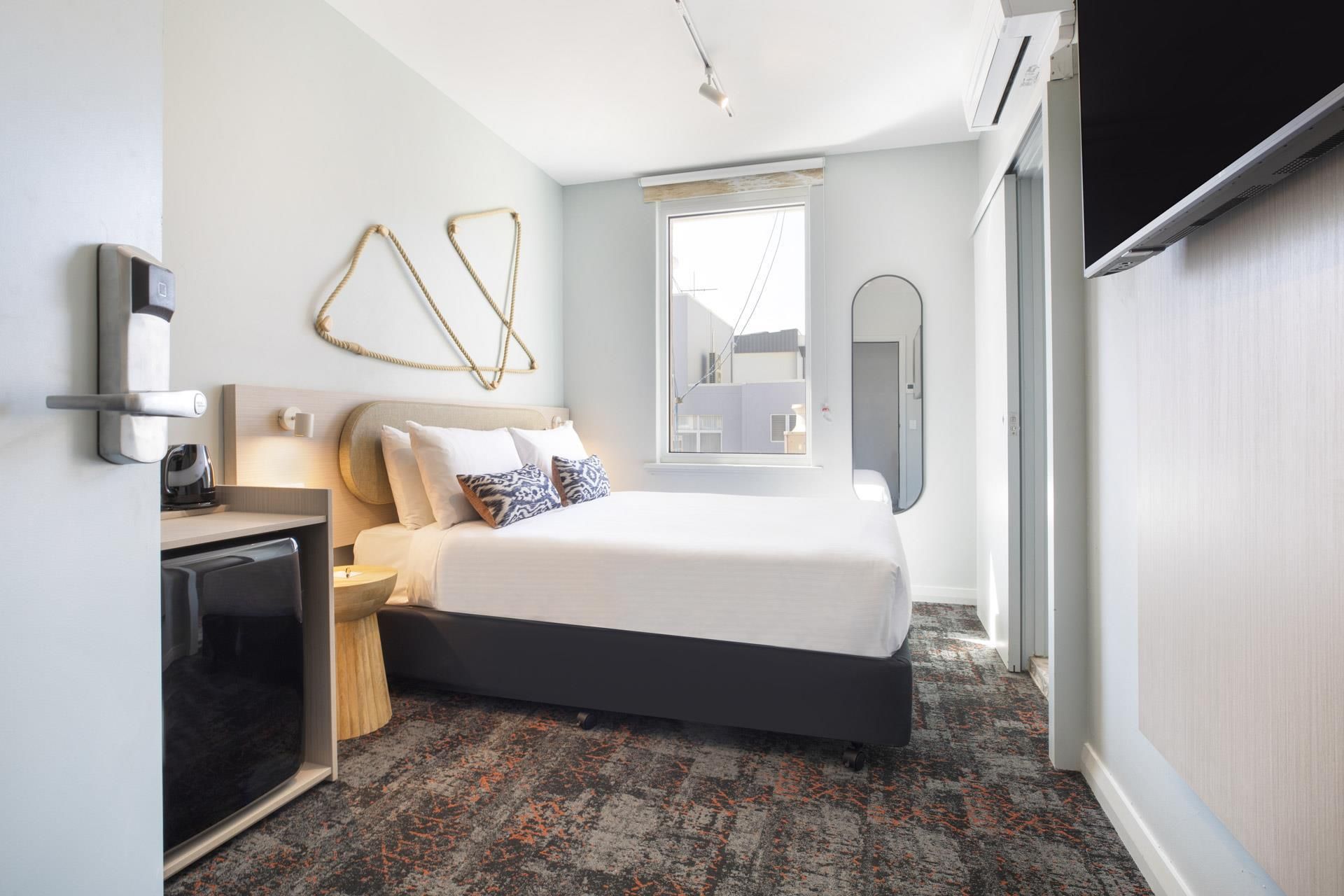 A modern hotel room with a bed, bedside table, and a television.
