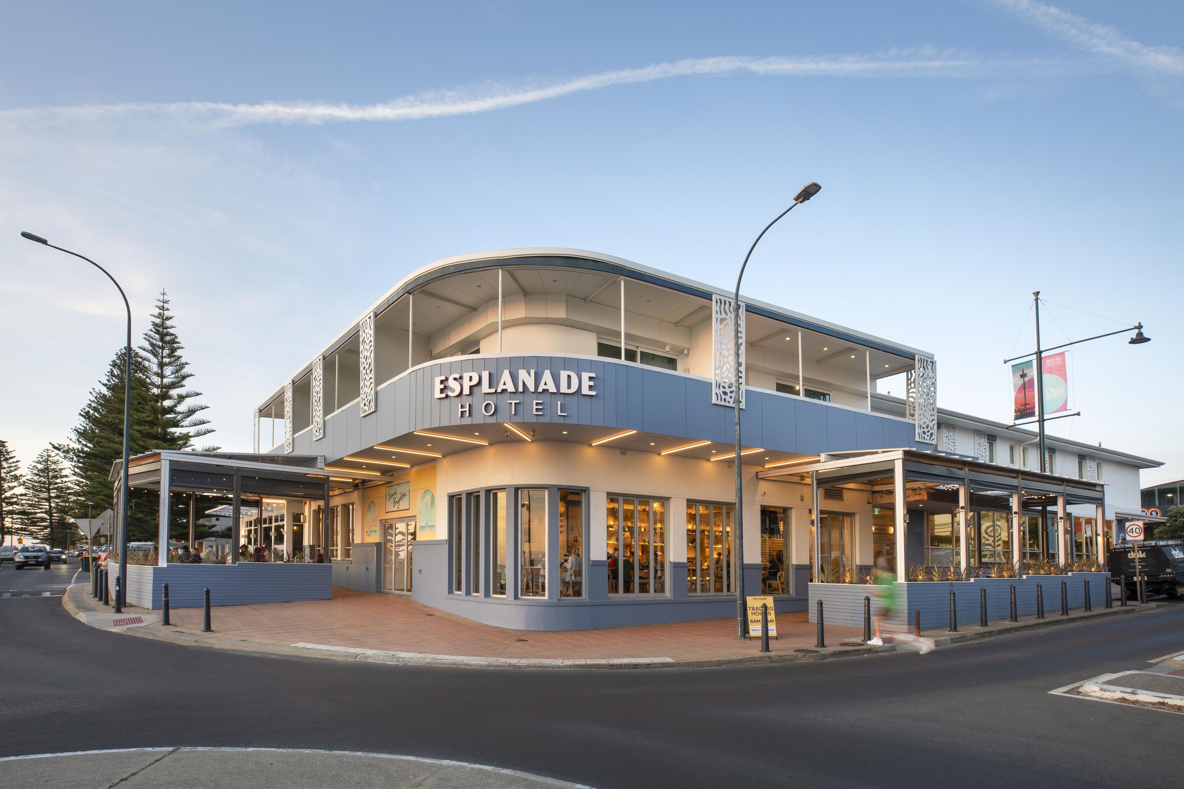 A modern hotel with a curved facade, large windows, and a covered entrance area.